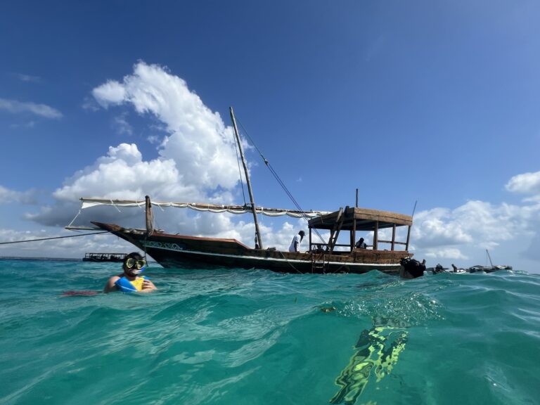 Snorkelling excursion near Zanzibar with traditional dhow sailing boat in the background